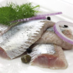 pickled herring, cold appetizer on white dish