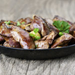 Chicken liver in frying pan on wooden table