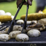 Mushrooms being grilled and handled with tongs close up