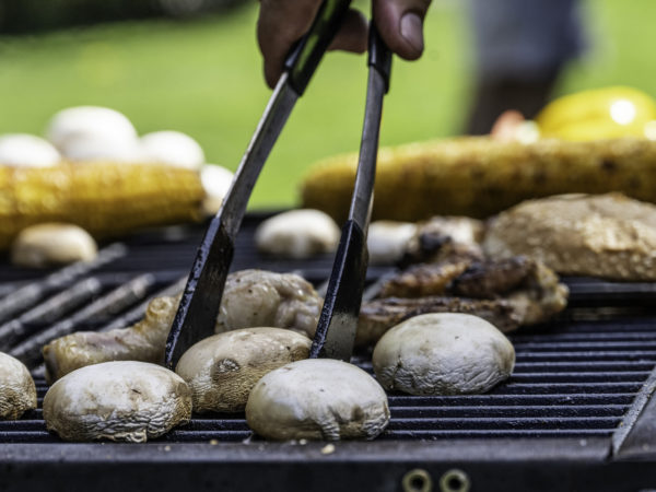 Mushrooms being grilled and handled with tongs close up